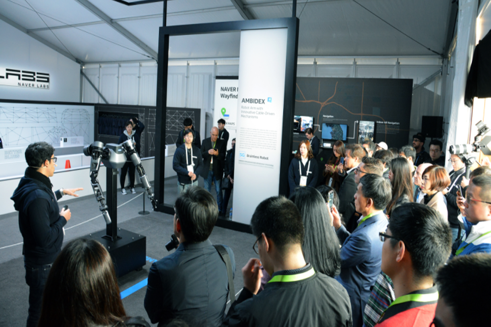 네이버와 네이버랩스 부스 방문객들이 로봇팔 앰비덱스의 시연을 관람하고 있다. (네이버)