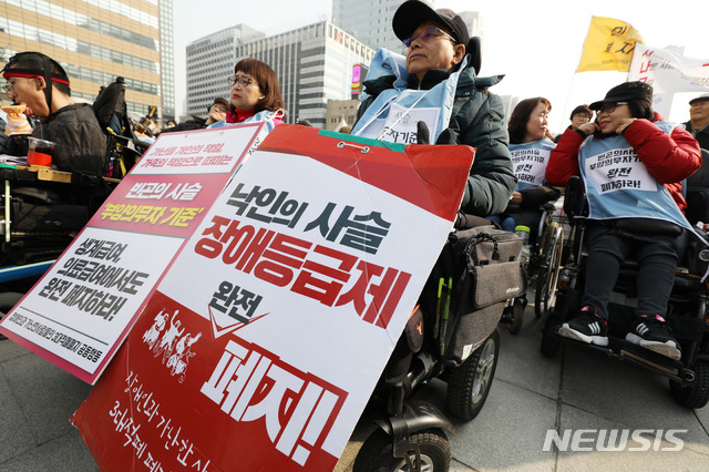 【서울=뉴시스】박미소 기자 = 28일 오후 서울 종로구 광화문 광장 앞에서 열린 '송파 세모녀 5주기 추모제'에서 시민들이 '장애등급제 폐지'와 '부양의무자 기준 폐지'와 관련한 피켓을 들고 있다.  이날 열린 추모제에서 이들은 부양의무자기준의 완전한 폐지 계획과 실질적인 빈곤해결을 위한 대책들을 조속히 수립할 것을 정부에 촉구했다. 2019.02.28.  misocamera@newsis.com
