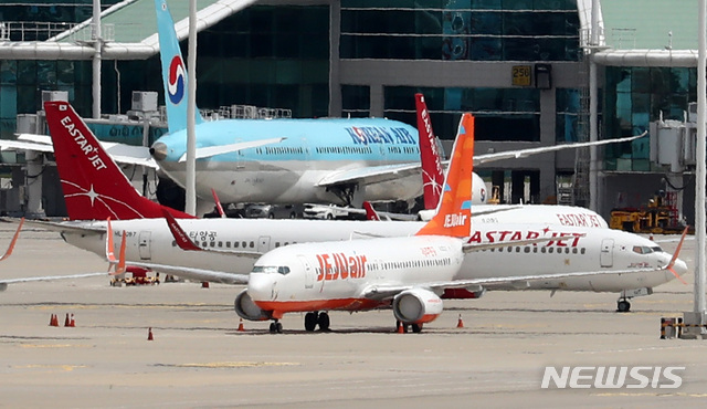 [인천공항=뉴시스] 이영환 기자 =  제주항공이 이스타항공에 통보한 인수합병(M&A) 선결 조건 이행 시한을 하루 앞둔 14일 오전 인천국제공항 여객터미널에 제주항공 비행기와 이스타항공 비행기가 멈춰 서 있다. 항공업계에 따르면 제주항공은 지난 1일 이스타항공에 "영업일 기준 10일 안에 미지급금 해소 등 선결조건을 이행하지  않을 시 계약을 파기할 수 있다"는 내용을 담은 공문을 보냈으며 이스타항공이 15일까지 250억원가량의 체불임금을 포함한 1700억원대의 미지급금을 갚아야 한다는 의미다. 2020.07.14. 20hwan@newsis.com