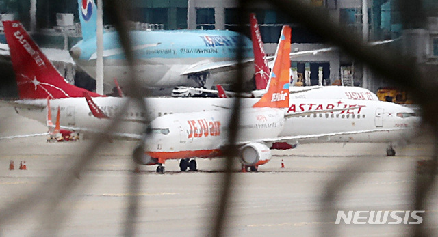 [인천공항=뉴시스] 이영환 기자 =  제주항공이 이스타항공에 통보한 인수합병(M&A) 선결 조건 이행 시한을 하루 앞둔 14일 오전 인천국제공항 여객터미널에 제주항공 비행기와 이스타항공 비행기가 멈춰 서 있다. 항공업계에 따르면 제주항공은 지난 1일 이스타항공에 "영업일 기준 10일 안에 미지급금 해소 등 선결조건을 이행하지  않을 시 계약을 파기할 수 있다"는 내용을 담은 공문을 보냈으며 이스타항공이 15일까지 250억원가량의 체불임금을 포함한 1700억원대의 미지급금을 갚아야 한다는 의미다. 2020.07.14. 20hwan@newsis.com