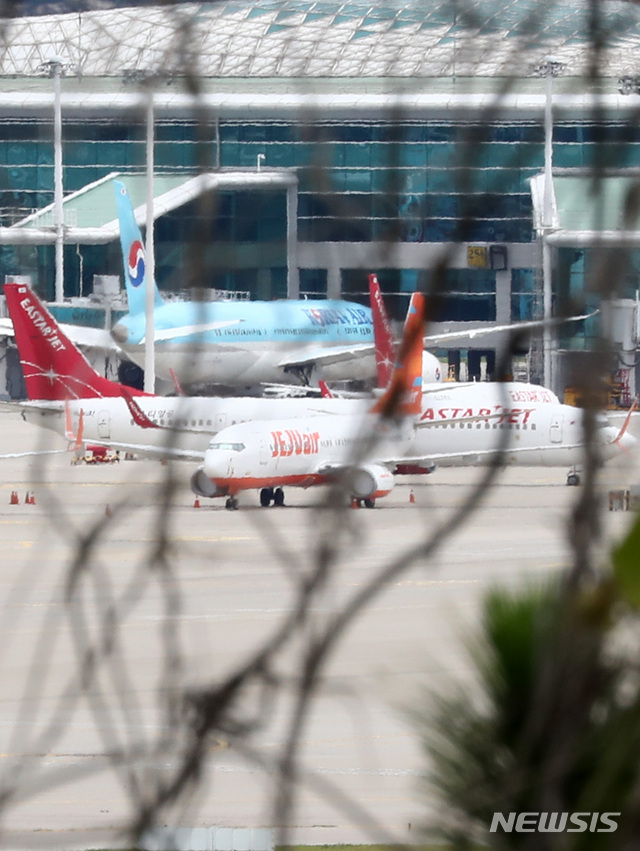 [인천공항=뉴시스] 이영환 기자 =  제주항공이 이스타항공에 통보한 인수합병(M&A) 선결 조건 이행 시한을 하루 앞둔 14일 오전 인천국제공항 여객터미널에 제주항공 비행기와 이스타항공 비행기가 멈춰 서 있다. 항공업계에 따르면 제주항공은 지난 1일 이스타항공에 "영업일 기준 10일 안에 미지급금 해소 등 선결조건을 이행하지  않을 시 계약을 파기할 수 있다"는 내용을 담은 공문을 보냈으며 이스타항공이 15일까지 250억원가량의 체불임금을 포함한 1700억원대의 미지급금을 갚아야 한다는 의미다. 2020.07.14. 20hwan@newsis.com