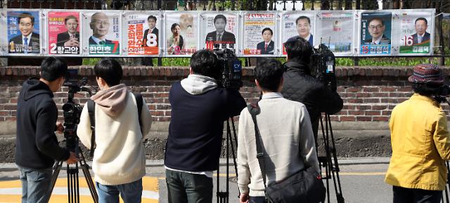 제21대 국회의원 선거운동이 시작된 2일 종로구 이화동에서 취재진이 선관위 관계자들이 선거벽보를 붙이는 것을 보고 있다.