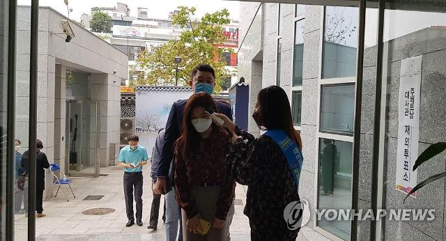 제21대 국회의원 선출을 위한 재외국민 투표가 시작된 지난 1일 베트남 수도 하노이 주베트남 한국대사관에 마련된 투표소에서 직원이 입장하는 유권자들의 체온을 측정하고 있다.