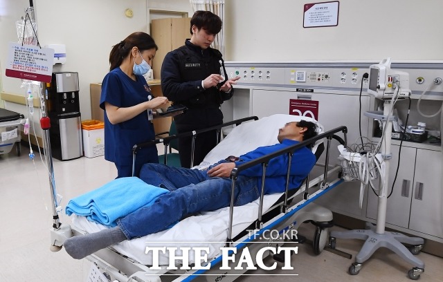 이날 119구급대가 이송한 한 취객은 퇴원을 포함한 모든 절차를 거부해 의료진을 난감하게 만들었다. 자의퇴원서를 안내하는 수련의와 그를 보호하기 위해 선 보안팀 직원. /이동률 기자