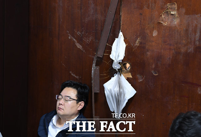 김성원 의원이 기대고 있는 의안과 출입문이 파손돼있다.