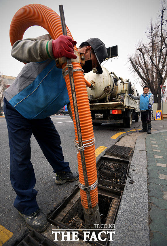 3월 6일 서울 용산구 갈월동에서 구청 관계자들이 쓰레기로 가득 찬 배수구를 청소하고 있다.