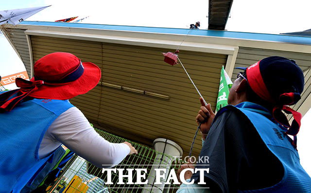 노조원들이 톨게이트 캐노피 위로 고공농성자들에게 생활용품을 전달하고 있다.