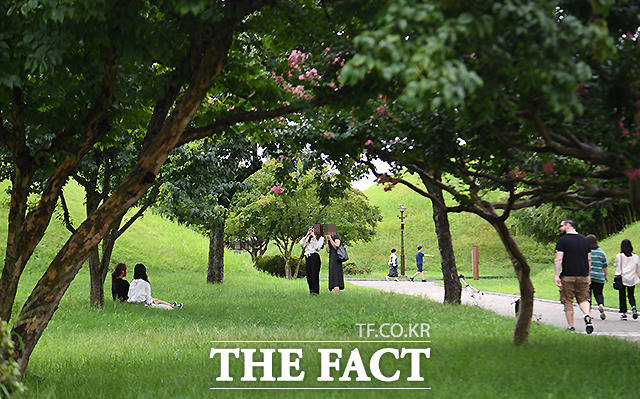 외국인 관광객(오른쪽)이 잔디밭에 앉아 있는 여성들을 바라보며 지나가고 있다.