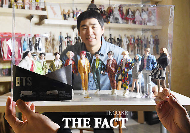 자신의 스타일로 재탄생시킨 인형들과 인형 케이스 앞에서 포즈를 취한 김태기 작가.