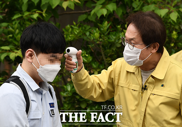 코로나19로 등교 개학이 미뤄진 지 80일만에 등교를 시작한 20일 오전 서울 종로구 경복고등학교에서 조희연 교육감(오른쪽)이 등교하는 고3 학생에게 발열 체크를 하고 있다. /이동률 기자