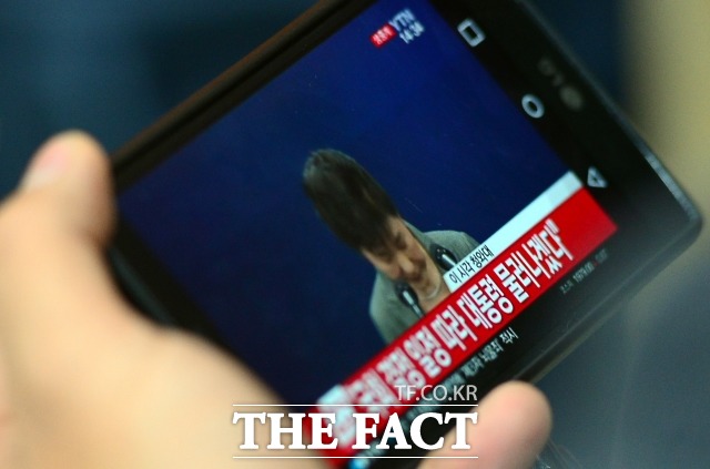 지난 2016년 11월 한 시민이 서울 여의도 새누리당사에서 한 취재진이 휴대전화로 박 전 대통령의 제3차 대국민담화를 보고 있는 모습. 박 전 대통령은 이날 담화에서 "저는 대통령직 임기 단축을 포함한 진퇴 문제를 국회 결정에 맡기겠다"고 밝혔다. /이새롬 기자
