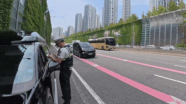 승차인원 미준수 차량을 단속 중인 최원조 경사 뒤로 차량들이 빠르게 지나가고 있다. 그 뒤엔 김형곤 반장이 차량을 통제하고 있다. 이영기 기자.